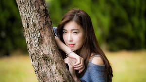 Asian Women Leaning On Tree Trunk Wallpaper