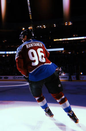 Back Shot Of Mikko Rantanen Leaning To The Left Under The Spotlight Wallpaper