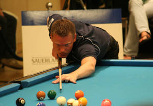 Billiards Athlete With Pool Stick On Blue Pool Table. Wallpaper