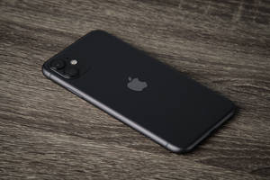 Black Iphone 7 On Brown Wooden Table Wallpaper