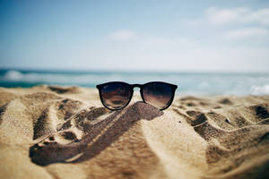 Black Ray-ban Wayfarer Sunglasses On Beach Sand Wallpaper