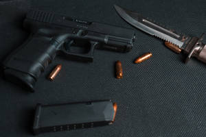 Black Semi Automatic Pistol Beside Brown And Silver Pocket Knife Wallpaper