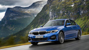 Blue Bmw Driving Through The Mountains Wallpaper