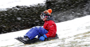 Boy Sledding Down The Snow Wallpaper