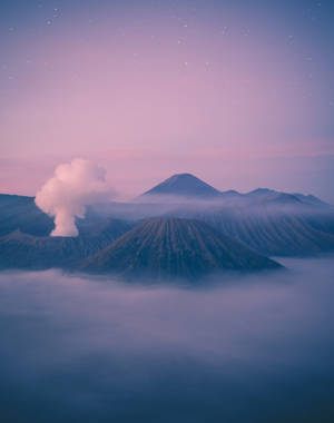 Bright Pastel Clouds Hovering Over A Mountain Peak Wallpaper