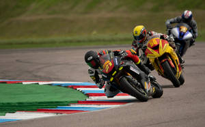 Caption: Dynamic Superbike Racing On Track Wallpaper