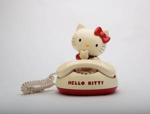 Caption: Interactive Hello Kitty At Desk With Telephone Wallpaper Wallpaper
