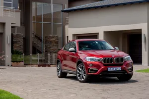 Caption: Luxurious Bmw X6 M Parked Outside A Modern House Wallpaper