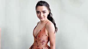 Caption: Maisie Williams Wearing A Formal Dress And Smiling At The Camera During An Event Wallpaper