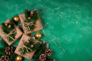 Christmas Gifts On Green Background With Pine Cones And Pine Branches Wallpaper