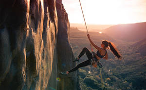 Climbing Woman On Mountain Side Wallpaper