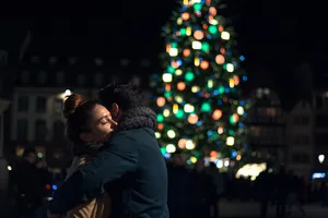 Couple Hugging By A Christmas Tree Wallpaper