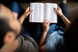 Couple Reading Book On Couch Wallpaper