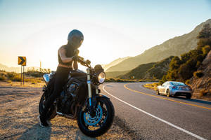 Daring Bike Rider Cruising Down The Roadside Wallpaper