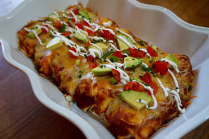 Delicious Enchiladas Topped With Fresh Avocado And Tomato Wallpaper