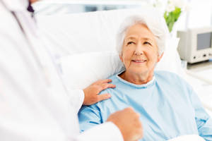 Elderly Female Patient Relaxing In Hospital Bed Wallpaper