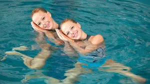 Elegance Redefined: Artistic Swimmers Showcasing A Sleeping Hand Gesture Wallpaper