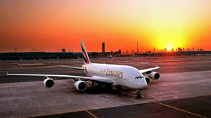 Emirates' Luxurious Airbus A380 Soars Through A Sunset Sky Wallpaper