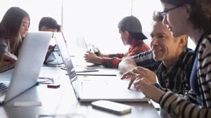 Engaged Learning - Teacher Assisting Student With Laptop Wallpaper