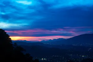 Enjoying The View Of The Majestic Mountain Range On A Blue Sky Day. Wallpaper