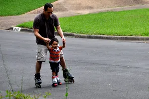 Father Teaching Son Rollerblading Wallpaper