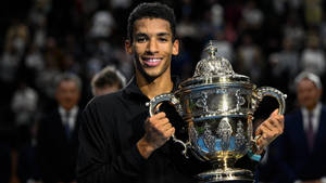 Felix Auger-aliassime Triumphantly Lifting A Trophy Wallpaper