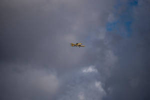 Freedom In The Sky: Small Yellow Plane Soaring High Wallpaper