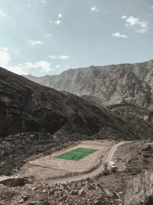 From High Atop The Mountain Range, Get A Glimpse Of A Football Stadium Below Wallpaper