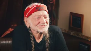 Iconic Singer Willie Nelson Posing With Braided Hair And Bandana Wallpaper