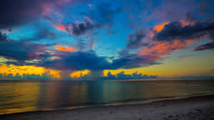 Image A Stunning View Of The Sun Setting Over A Beach Wallpaper