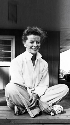 Katharine Hepburn Seated On A Wooden Floor Wallpaper