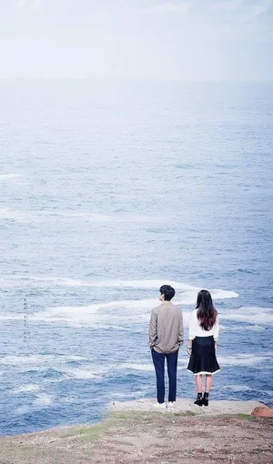 Korean Couple Standing Near The Ocean Wallpaper