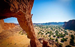 Long Shot Photo Of A Man Climbing Rock Wallpaper