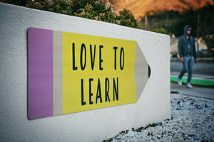 Love To Learn Pencil Signage On Wall Near Walking Man Wallpaper