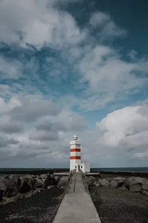 Majestic Lighthouse Under Gray Cloudy Skies Wallpaper