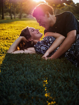 Man And Woman Lying On Green Grass Field During Daytime Wallpaper