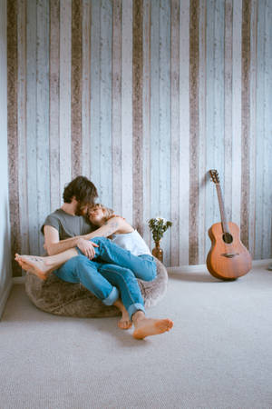 Man And Woman Sitting On Gray Beanbag Wallpaper