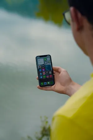 Man Holding A Black Iphone Ios 12 Wallpaper