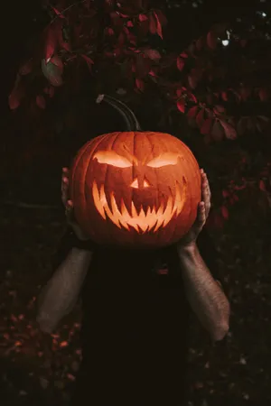 Man Holding Pumpkin For Halloween Night Wallpaper