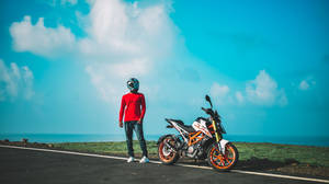 Man In Red Jacket And Blue Denim Jeans Standing Beside Black And White Motorcycle During Daytime Wallpaper