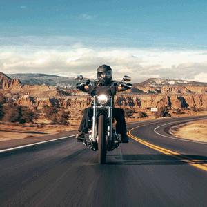 Man Rides Hd Motorcycle On Coastal Road Wallpaper