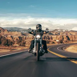 Man Rides Hd Motorcycle On Coastal Road Wallpaper