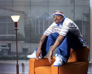 Man Seatedon Orange Couch Indoors Wallpaper