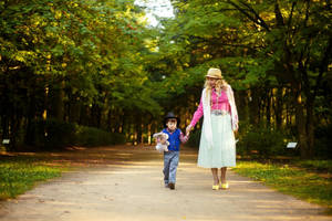 Mom And Son Holding Hands In Park Wallpaper