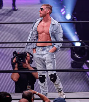 Orange Cassidy In Deep Thought Beside A Cameraman Wallpaper