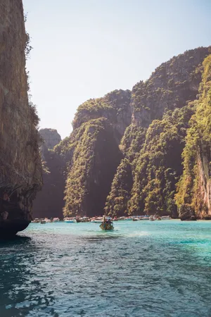 People Riding Boat On Sea Near Brown Rocky Mountain During Daytime Wallpaper