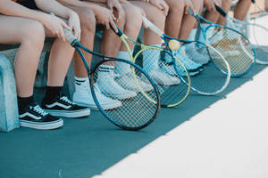 Person In Black And White Nike Sneakers Holding Blue And White Tennis Racket Wallpaper
