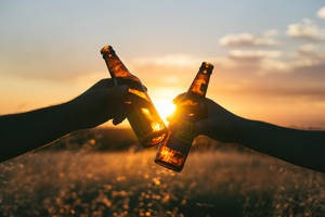 Photography Of Person Holding Glass Bottles During Sunset Wallpaper