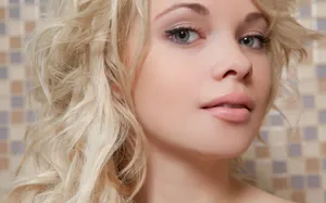 Radiant Blonde Female Model Against A Chic Tiled Background Wallpaper