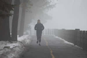 Random Person Jogging On Misty Road Wallpaper
